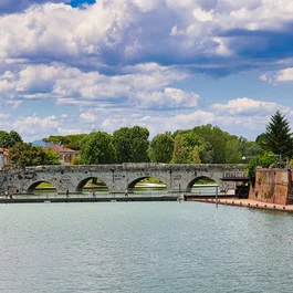 Hotel Regal: comfort ed eleganza a Rimini Ponte storico in pietra con archi sul canale fiancheggiato da alberi e case
