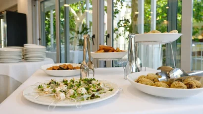 Hotel Regal: comfort ed eleganza a Rimini Buffet di antipasti con piatti bianchi su tavolo bianco vicino a grandi finestre