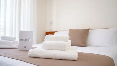 Hotel Regal: comfort ed eleganza a Rimini Pila di asciugamani bianchi su un letto con copriletto marrone e cuscino in una stanza d'hotel